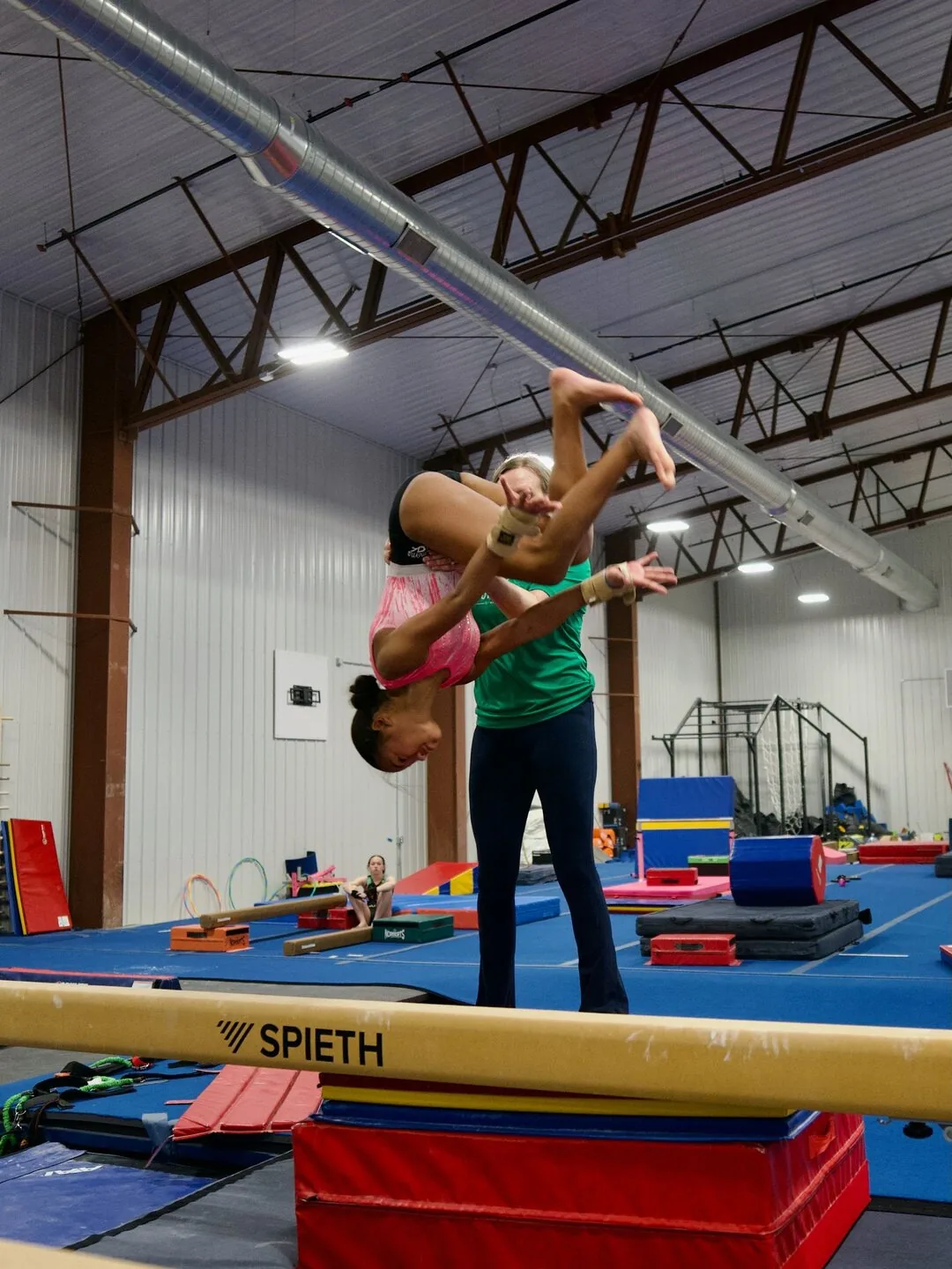 A coach spotting a gymnast on the high bar