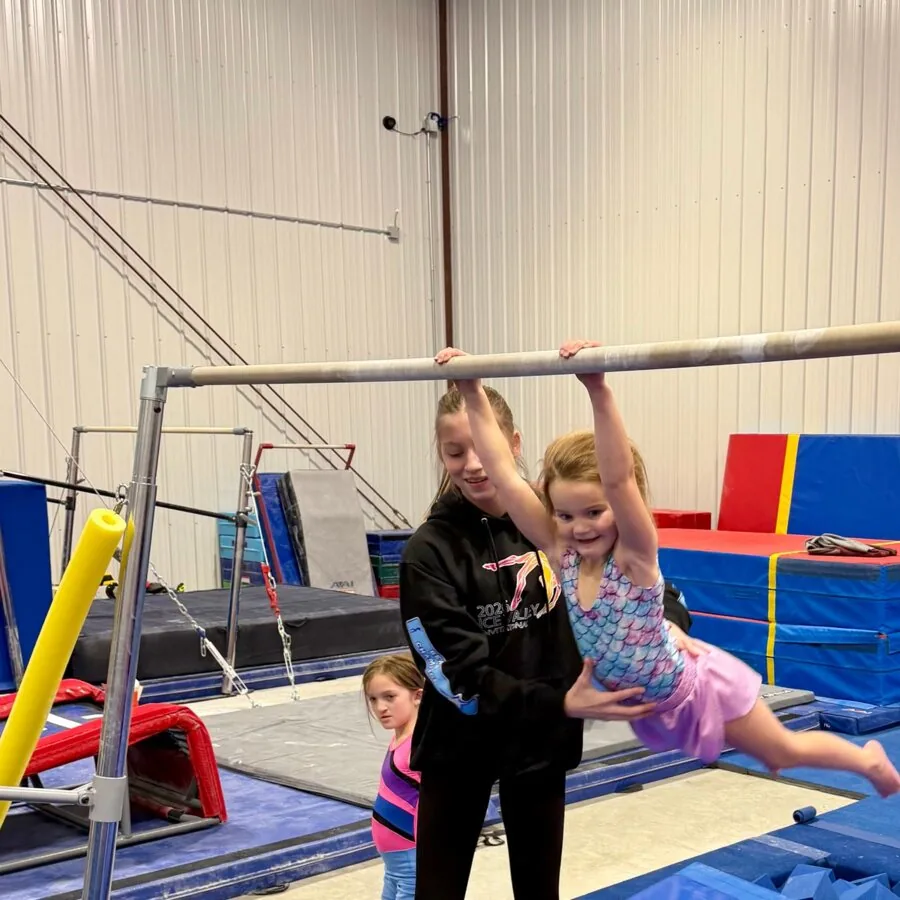 Gymnasts practicing handstands against the wall on red mats