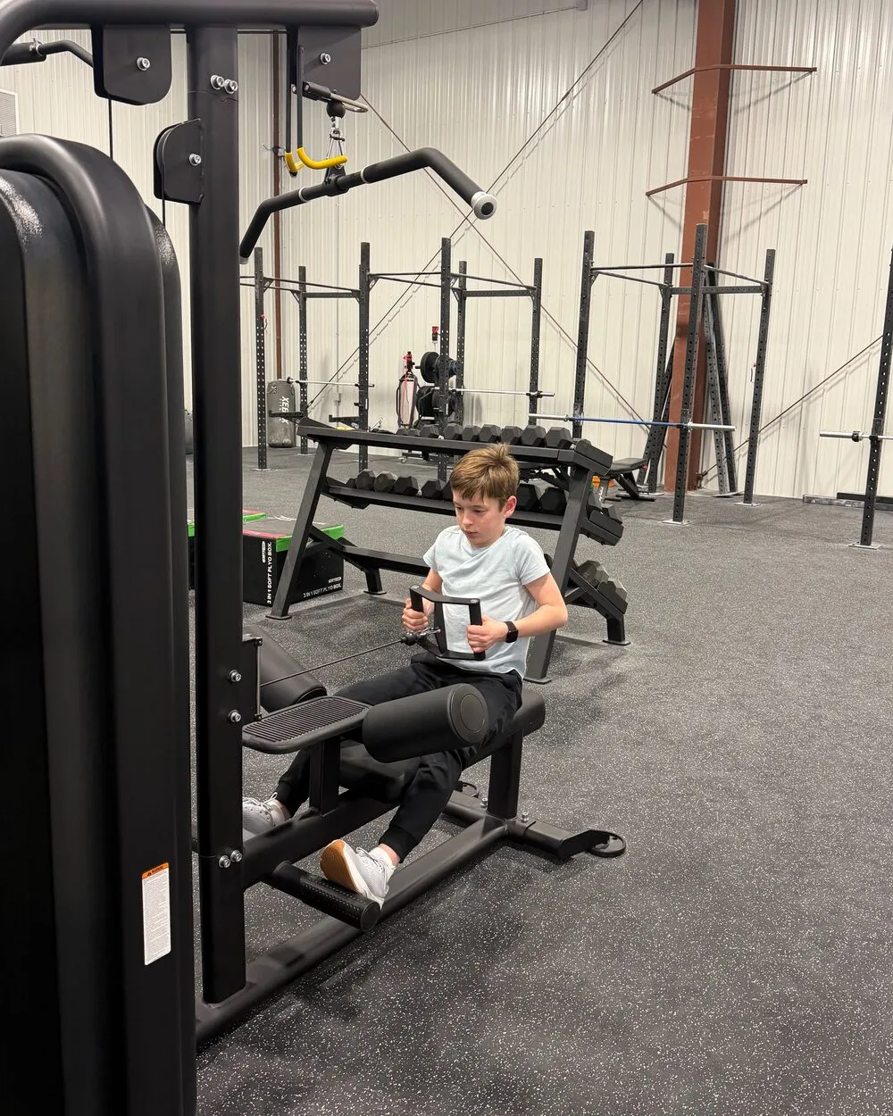 A child training on a seated weight machine in the youth fitness room