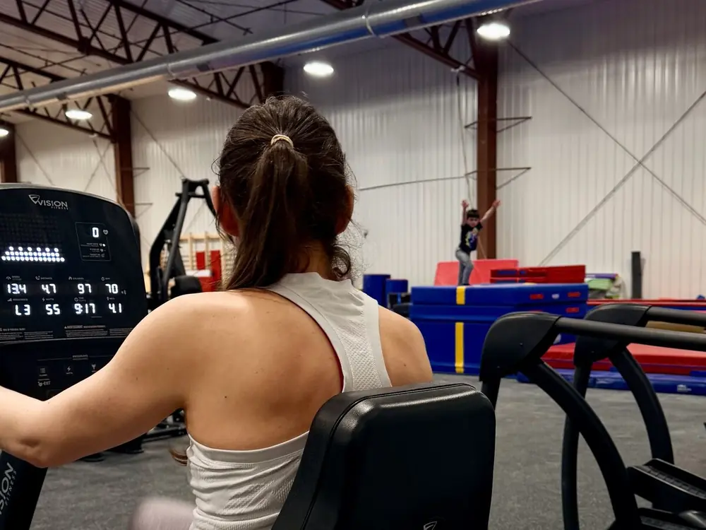 An adult on the elliptical in the Fitness Zone overlooking the gym floor
