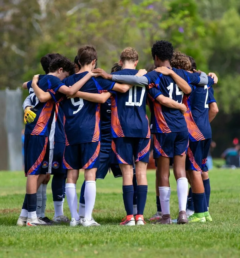 A boys' soccer team in a huddle on the field