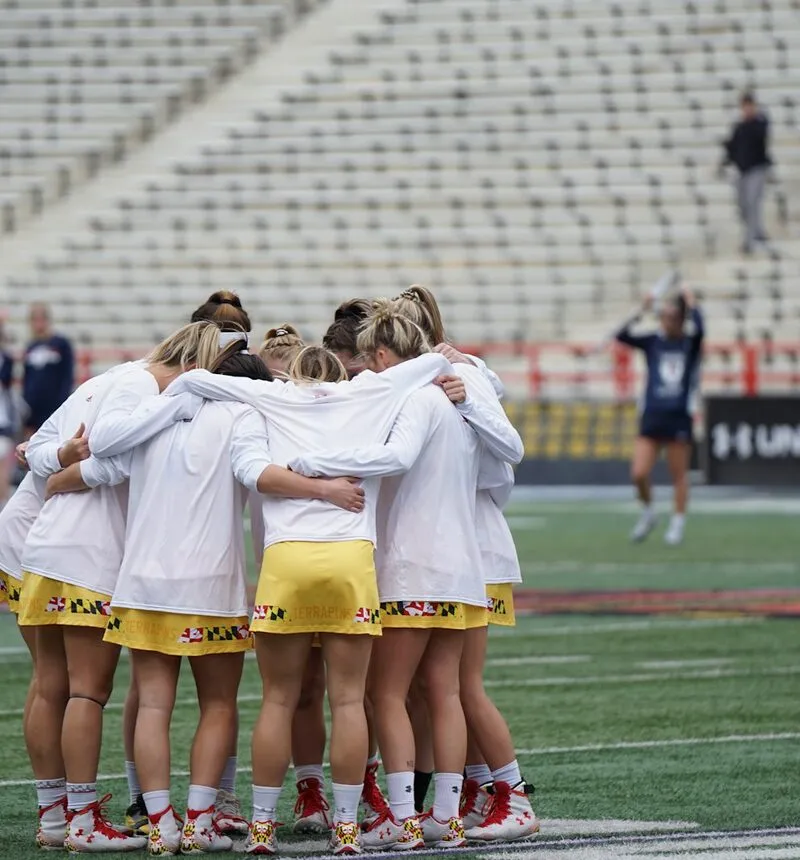 A girls' sports team in a huddle on the field